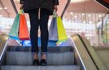 Woman legs with colorful shopping bags on the escalator in a shopping mall