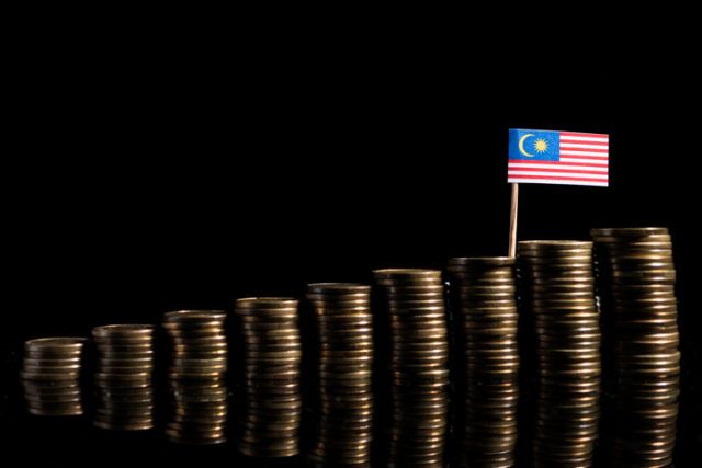 Malaysian flag with lot of coins isolated on black background