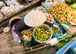 Vietnamese woman selling fruit on floating market, Mekong River Delta,