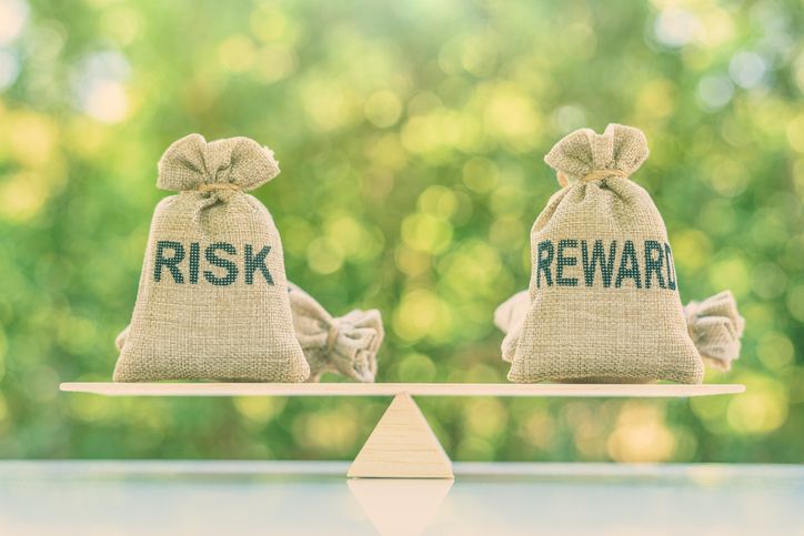 Risk reward ratio / risk management concept : Risk and reward bags on a basic balance scale in equal position, depicts investors use a risk reward ratio to compare the expected return of an investment