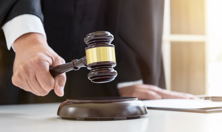 Close up of Male lawyer or judge hand’s striking the gavel on sounding block, working with Law books, report the case on table in modern office, Law and justice concept