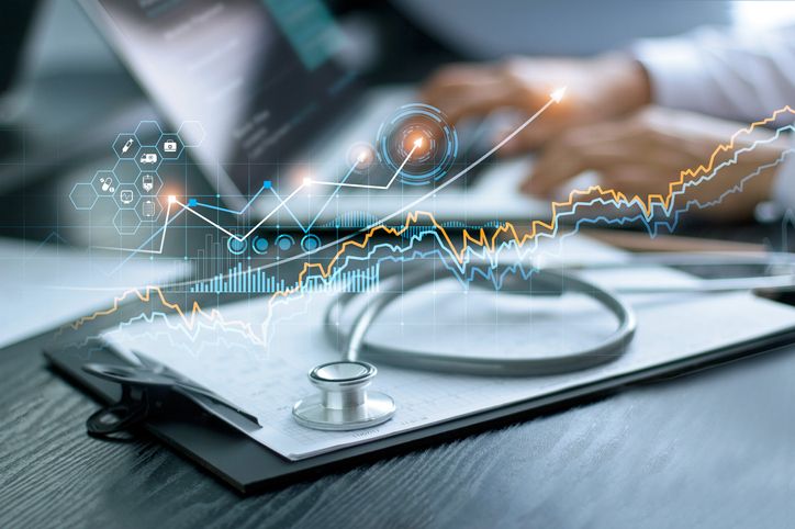 Healthcare business graph data and growth, Stethoscope with doctor’s health report clipboard on table, Medical examination and doctor analyzing medical report on laptop screen.