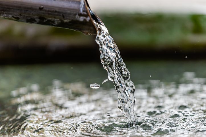 Purification water fountain in Kyoto, Japan with liquid running from spout faucet closeup