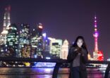 young asian woman plays with mobile phone in modern city