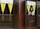 A Malay Muslim Woman Standing by The Window and Using Mobile Phone