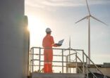 Man engineer working and holding the laptop for check performance of wind turbine farm Power Generator Station, Concept of sustainable resources, Concept of professional for the energy industry