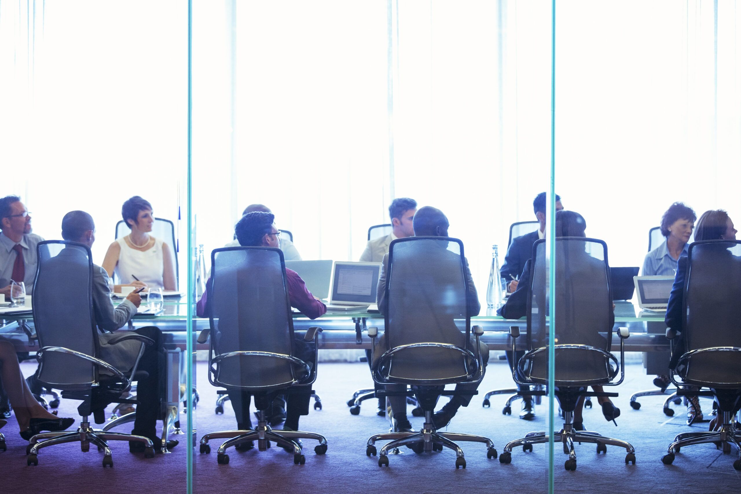 Business people having meeting in conference room, sitting with laptops and discussing