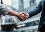 Meeting success. Two business persons shaking hands standing outside