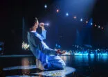 Pop Artist Performing Live Concert on Stage, Illuminated by a Spotlight. Epic Cinematic Performance Captures Artist’s Passion and Energy. Dark Background Creating a Dramatic Lonely Scene