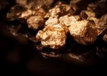 UOB AM launches blended physical gold and gold miner strategy Gold nuggets on black background.